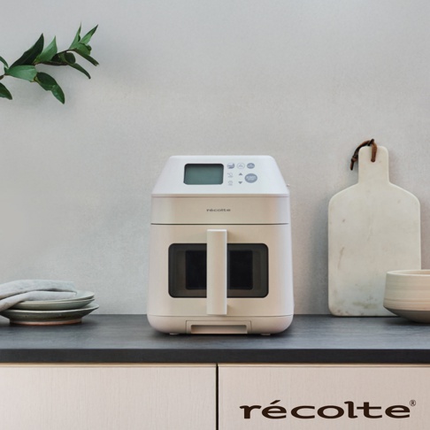recolte 麗克特 Hi Steam Air Oven 蒸氣氣炸鍋 RAO-3 擺設在廚房檯面上，右側擺著一個木質砧板和一個碗，左側則堆疊著餐盤。