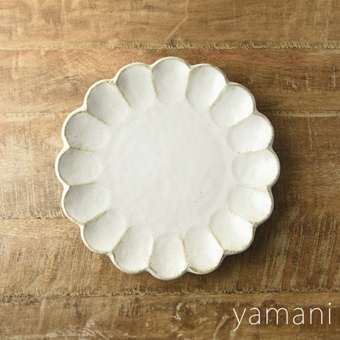 一個 24 公分、白色、帶有六瓣花型邊緣的陶瓷主食盤，表面有細微的紋理，盤底有「yamani」品牌標誌，置於木紋背景上。