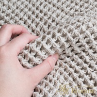 淺米色網格紋理浴墊，由柔軟的棉質材料製成，可透過指尖感受其紋理。