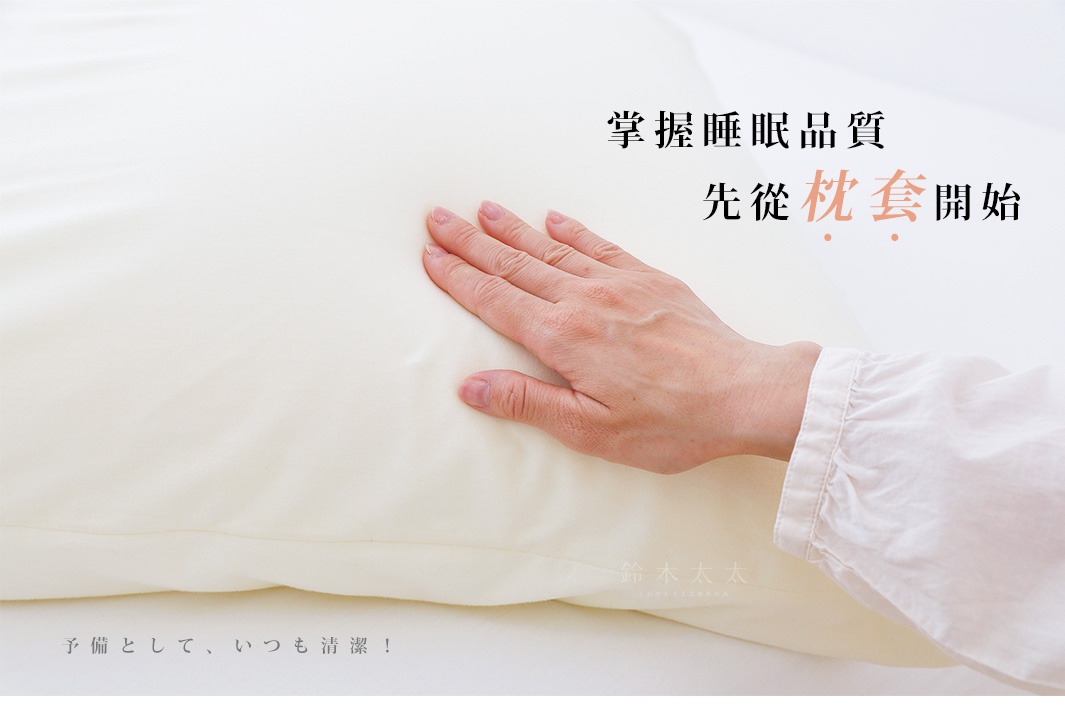 米白色的「王樣の雙面BIG夢枕」專用枕套，質地柔軟，表面有輕微的紋理。一只手輕撫在枕套上，展示其觸感。