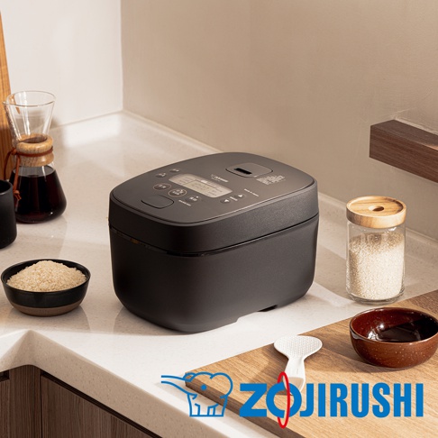 象印IH電子鍋，黑色機身，頂部有數位顯示螢幕與操作按鈕，旁邊擺放一碗生米、一罐米、一個飯勺和一個日式碗。