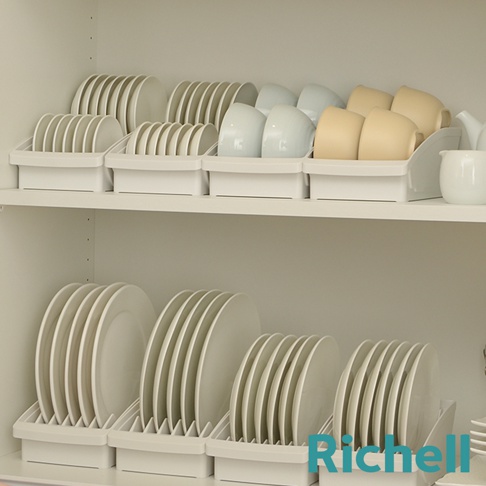 櫥櫃內擺放著多個白色收納架，架上整齊收納著各種白色、淺藍色和淺黃色的盤子和杯子，最右側還有一個白色茶壺。