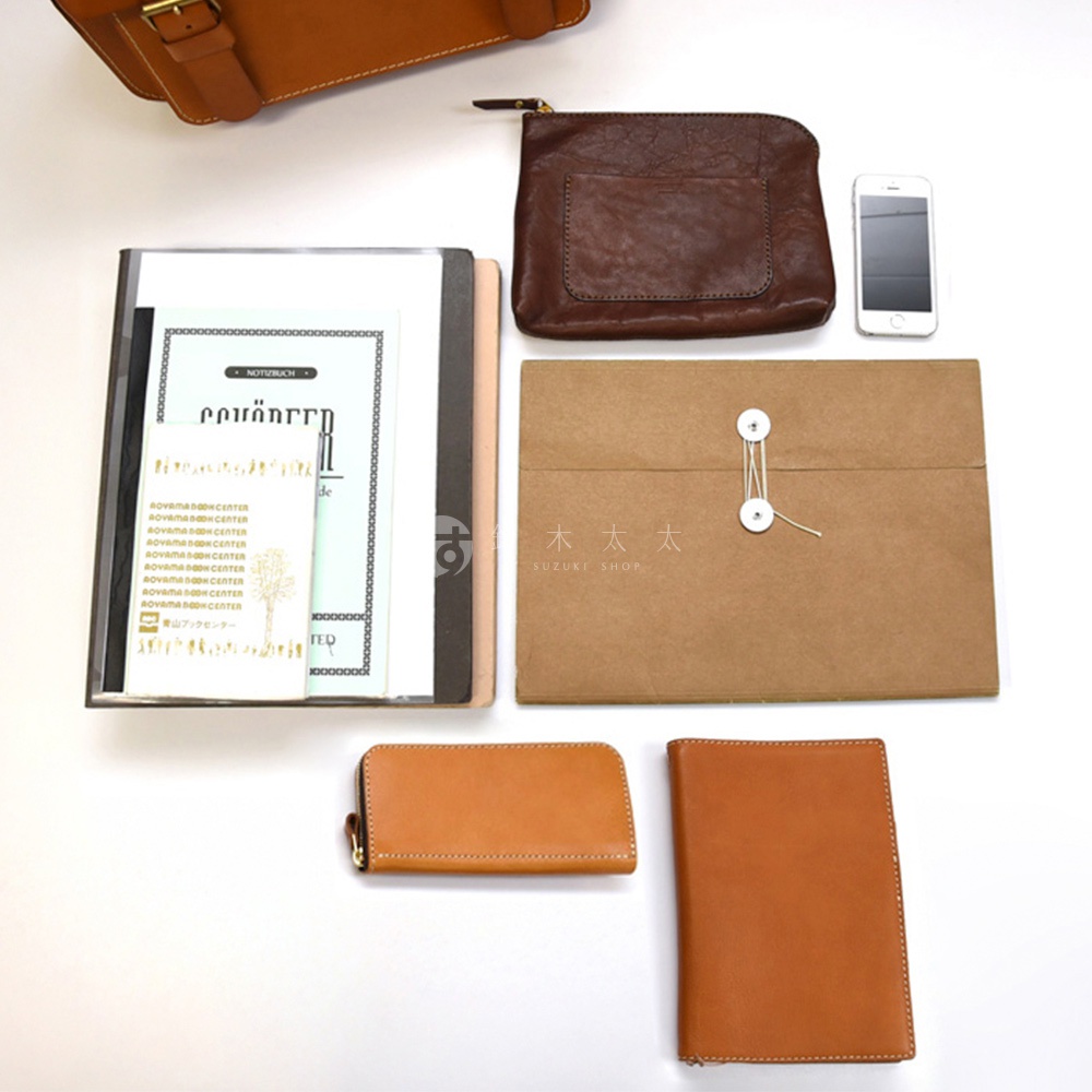 皮革製雙扣兩用單肩包，內含筆記本、手機、文件夾與零錢包，展現職人手作質感。