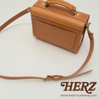 棕色皮革製成的迷你兩用包，有提把和可拆卸肩帶，包身前方有一個平整的置物袋，並有品牌標誌。