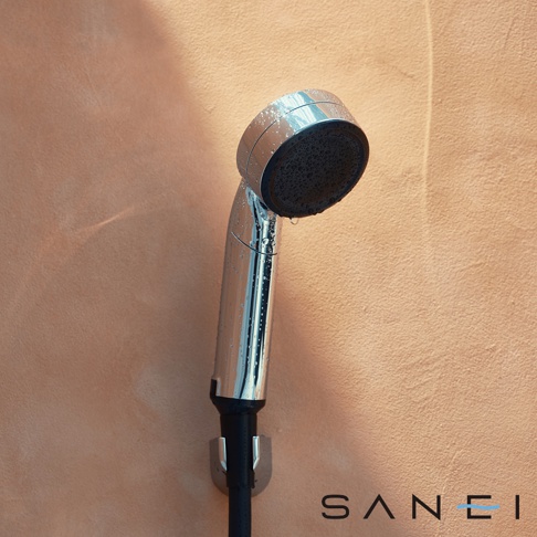 銀色金屬材質的 SUIN 超微氣泡蓮蓬頭，帶有黑色噴頭，表面有水珠，固定在牆上。