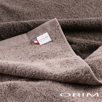 BULKY PRO今治沙龍浴巾，採用柔軟的純棉材質，呈現深淺兩種大地色調，毛圈蓬鬆，質感厚實。浴巾一角縫有品牌標籤，標籤上印有ORIM字樣及網址，並帶有紅藍色條紋裝飾。