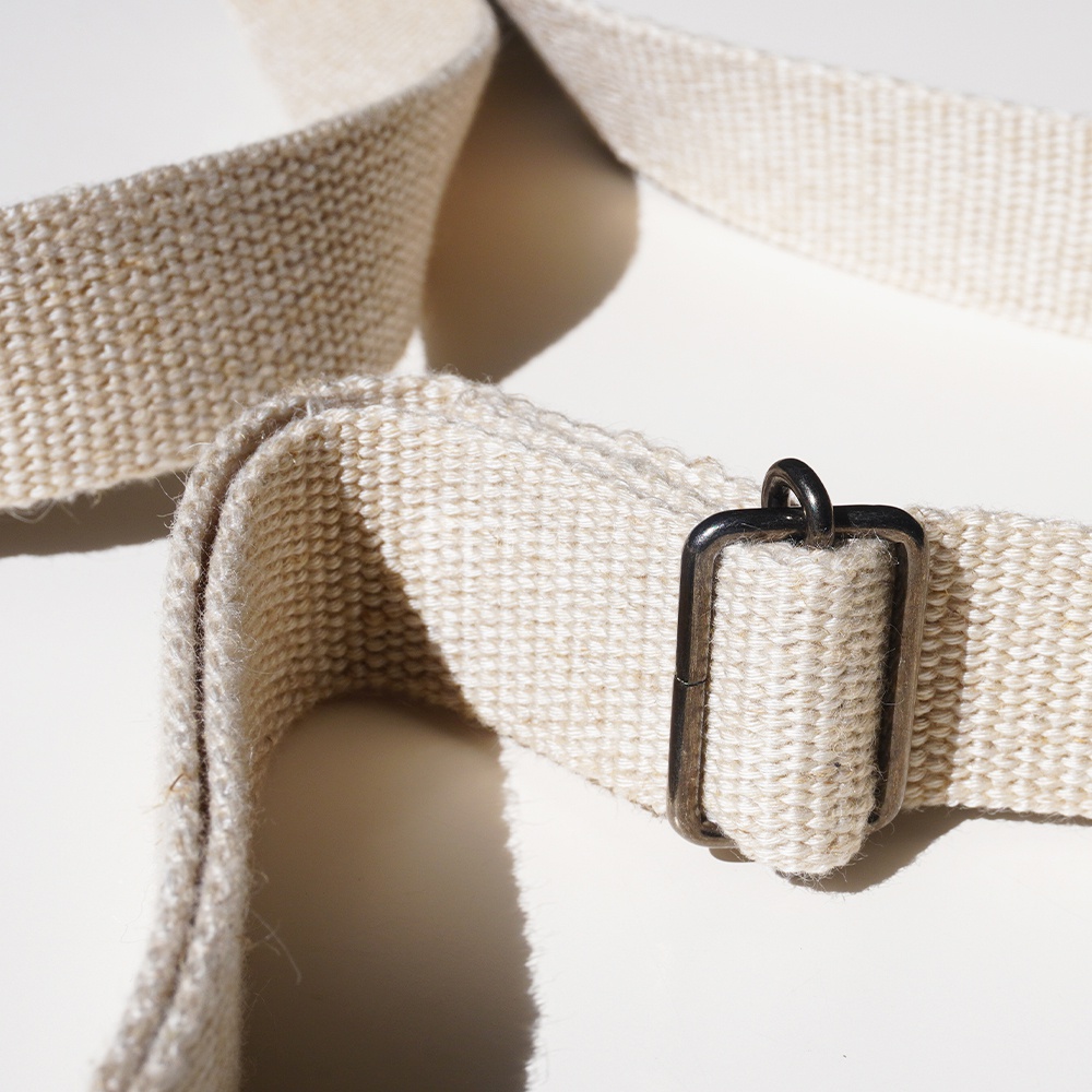 一條淺色織帶，帶有方形金屬扣環，近景特寫。