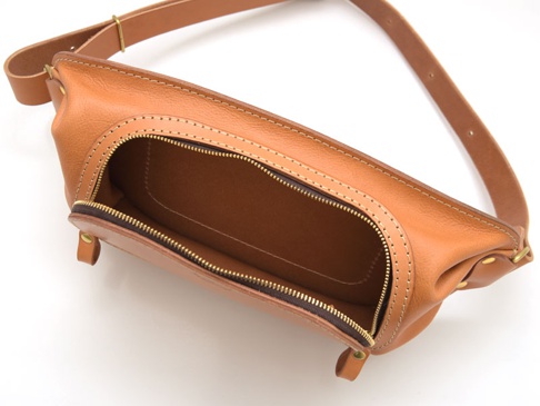 棕色皮革製成的斜背包，主拉鍊開口，展示內部，附有可調節的皮革肩帶。
