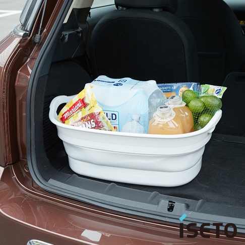 白色伸縮浴盆裝有雜貨，包括果汁、水瓶、酪梨和義大利麵。