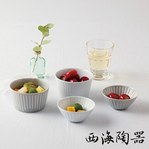 波佐見燒 FUWARI 四件式碗碟，包含三個白色陶瓷碗，分別裝有水果和紅色果實，以及一個附有蓋子的灰色陶瓷碗，內含水果。旁邊擺放著一杯飲品和一瓶綠色小花瓶。