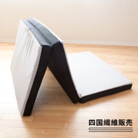 側躺專用三折床墊，白色網狀布料，黑色邊緣，呈現波浪紋理，可折疊，單人尺寸，放置在木質地板上。