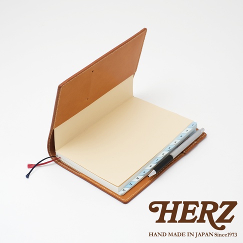 職人手作皮革B6記事本書套，採用棕色皮革製成，內含淺黃色筆記本，具備月份分隔標籤及一支筆。