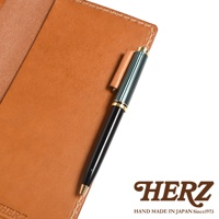 職人手作皮革輕便記事本書套，淺棕色皮革，附一支黑色筆桿、綠色條紋筆夾和金色筆頭的鋼筆，鋼筆固定在書套側邊。