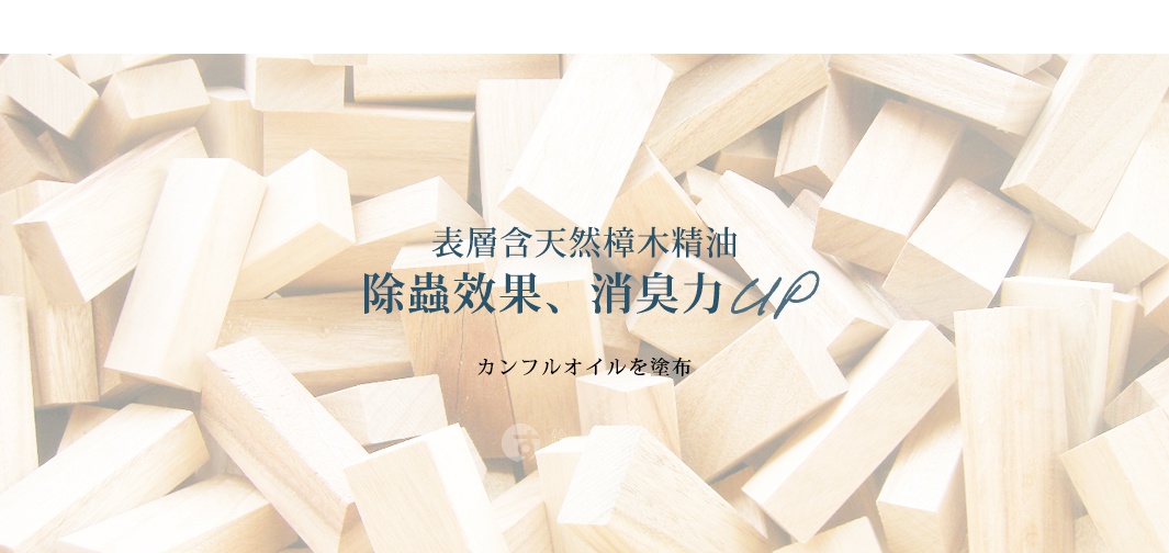 堆疊的淺色檜木塊，表面有文字「表層含天然樟木精油，除蟲效果、消臭力UP，樟腦油を塗布」。