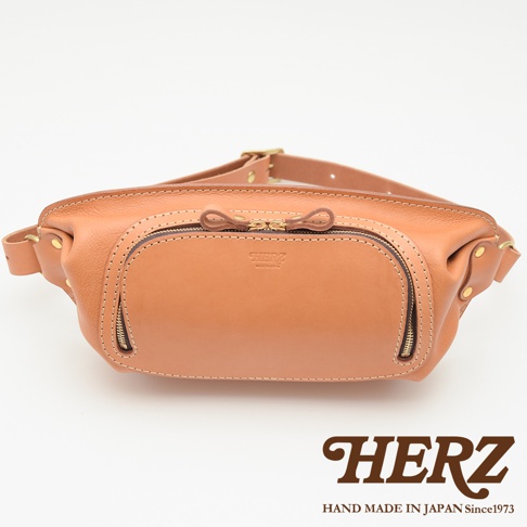 HERZ 職人手作皮革拉鍊旅行斜背包 F-7，棕褐色Stare皮革，正面有品牌壓印，設有雙拉鍊主袋與前置拉鍊暗袋。