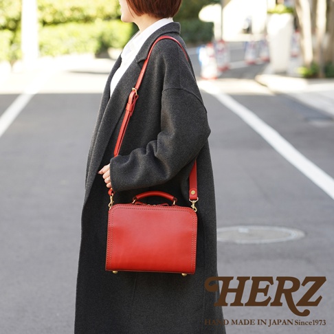 職人手作皮革兩用方形單肩包，採用紅色皮革製成，包身帶有手提把和可拆卸的肩帶，搭配金色金屬扣環。