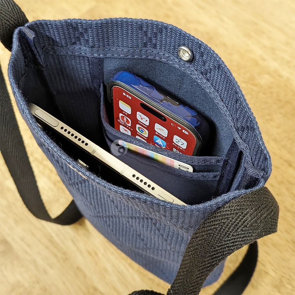 深藍色刺子織紋理的平板收納側背包，內有兩個隔層，分別放置一台平板電腦和一支手機。