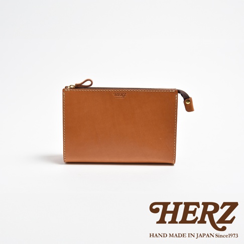 職人手作皮革三角底拉鍊手拿包，採用光滑棕色皮革製作，設有黃銅色拉鍊和同色系縫線。包身正面右上方印有品牌標誌。