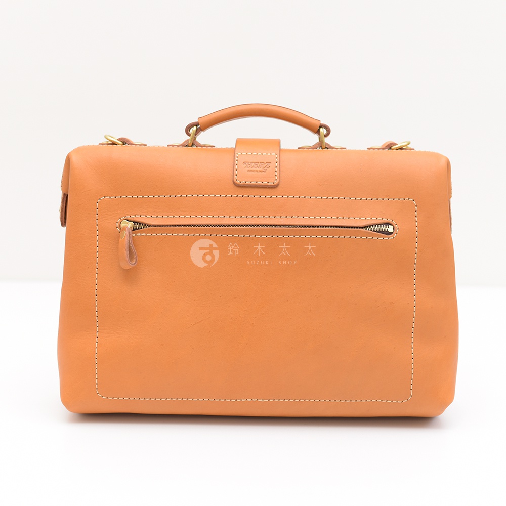 職人手作皮革軟式杜勒斯包，天然皮革材質，淺棕色，正面設有拉鍊口袋，頂部有手提把和金屬扣環。