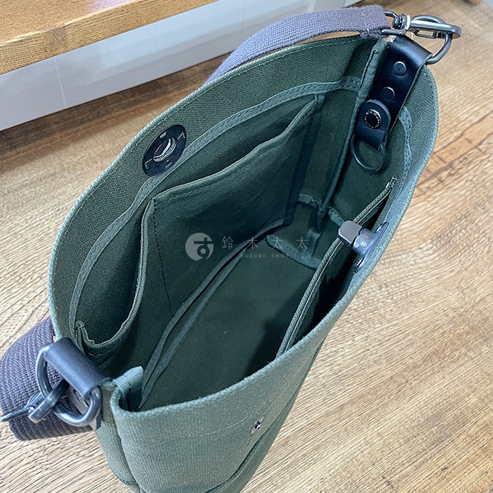 軍綠色純棉帆布迷你側背包，內有數個隔層，配有灰色織帶提把及皮革裝飾。