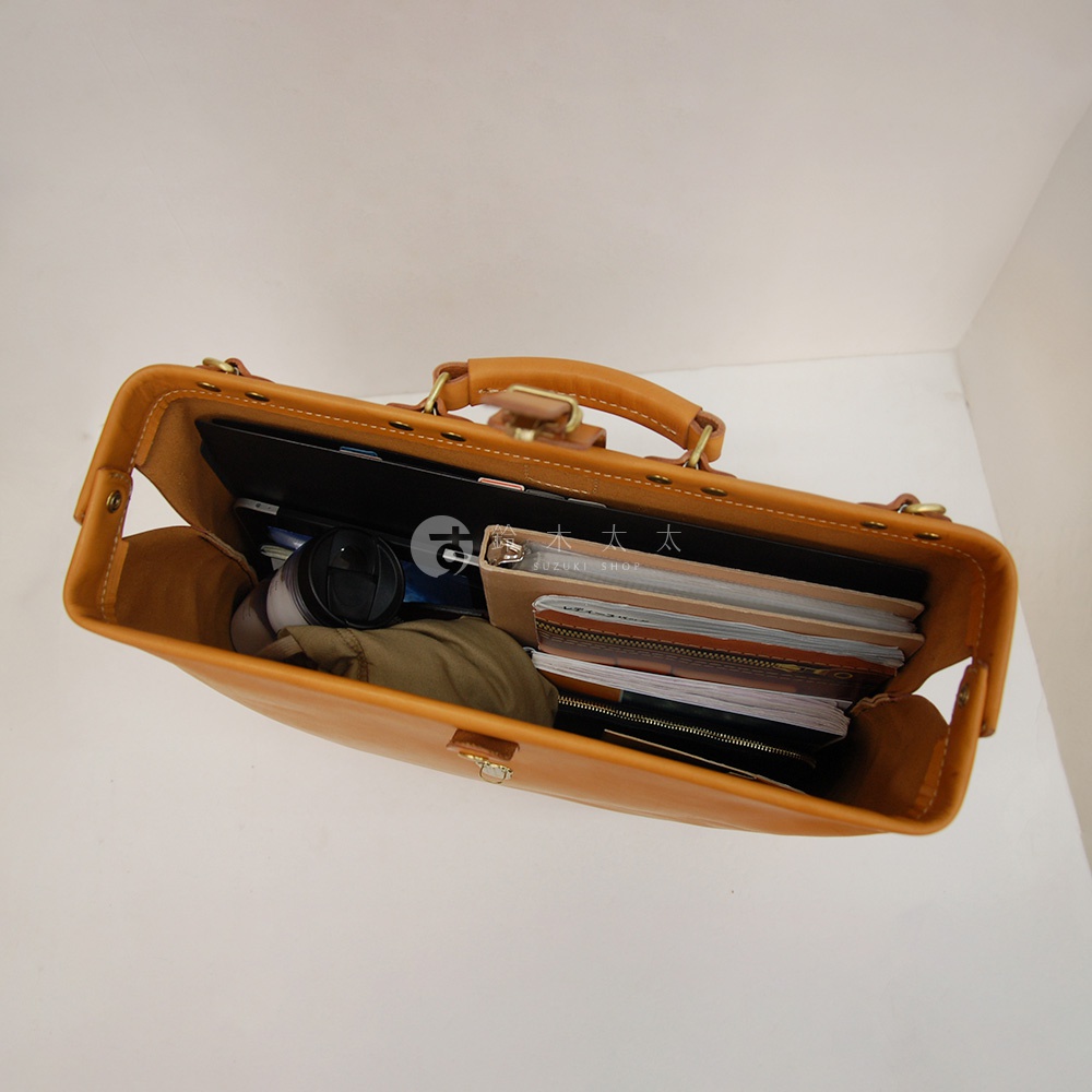 職人手作棕色皮革軟式杜勒斯包，內部裝有筆記本、平板電腦、水杯和衣物，展示其寬敞的收納空間。