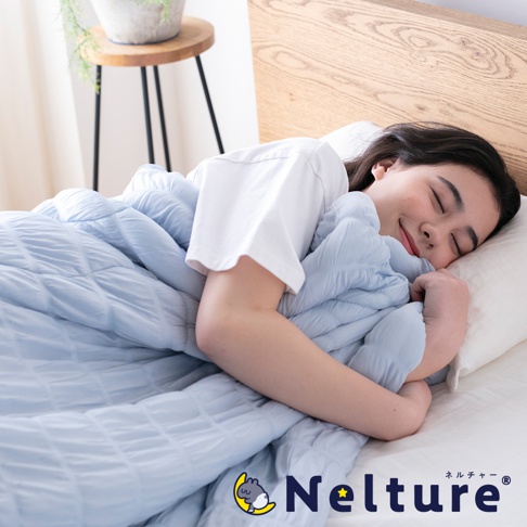 淺藍色菱格紋單人被，輕柔包裹著一位正在熟睡的年輕女性。被子材質看起來柔軟透氣，適合夏季使用。