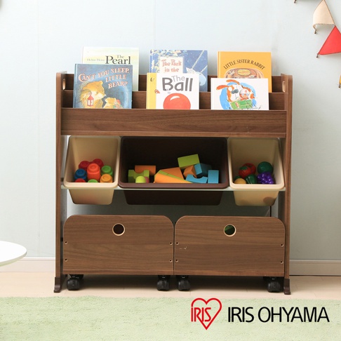 木製繪本收納架，附有兩個淺色收納盒，內有彩色玩具積木及其他小玩具。下方有兩個木製抽屜，附有輪子，可移動。