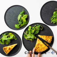 四個黑色圓形砧板盤，其中三個盤子中各盛有新鮮的綠葉沙拉，另外兩個盤子中各有一塊烘烤過的鹹派。