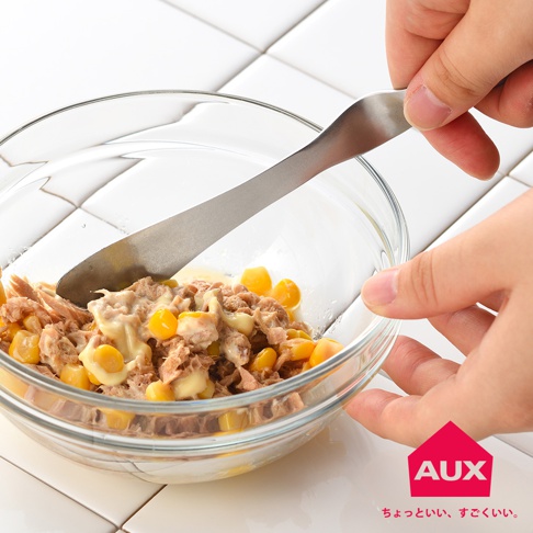 銀色金屬材質的抹刀，正在混合碗中的鮪魚玉米沙拉。