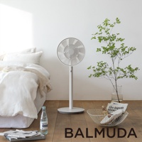 The GreenFan 風扇，白色，立式設計，圓形扇葉網罩，帶有纖細的直立支架和圓形底座，置於臥室環境中。