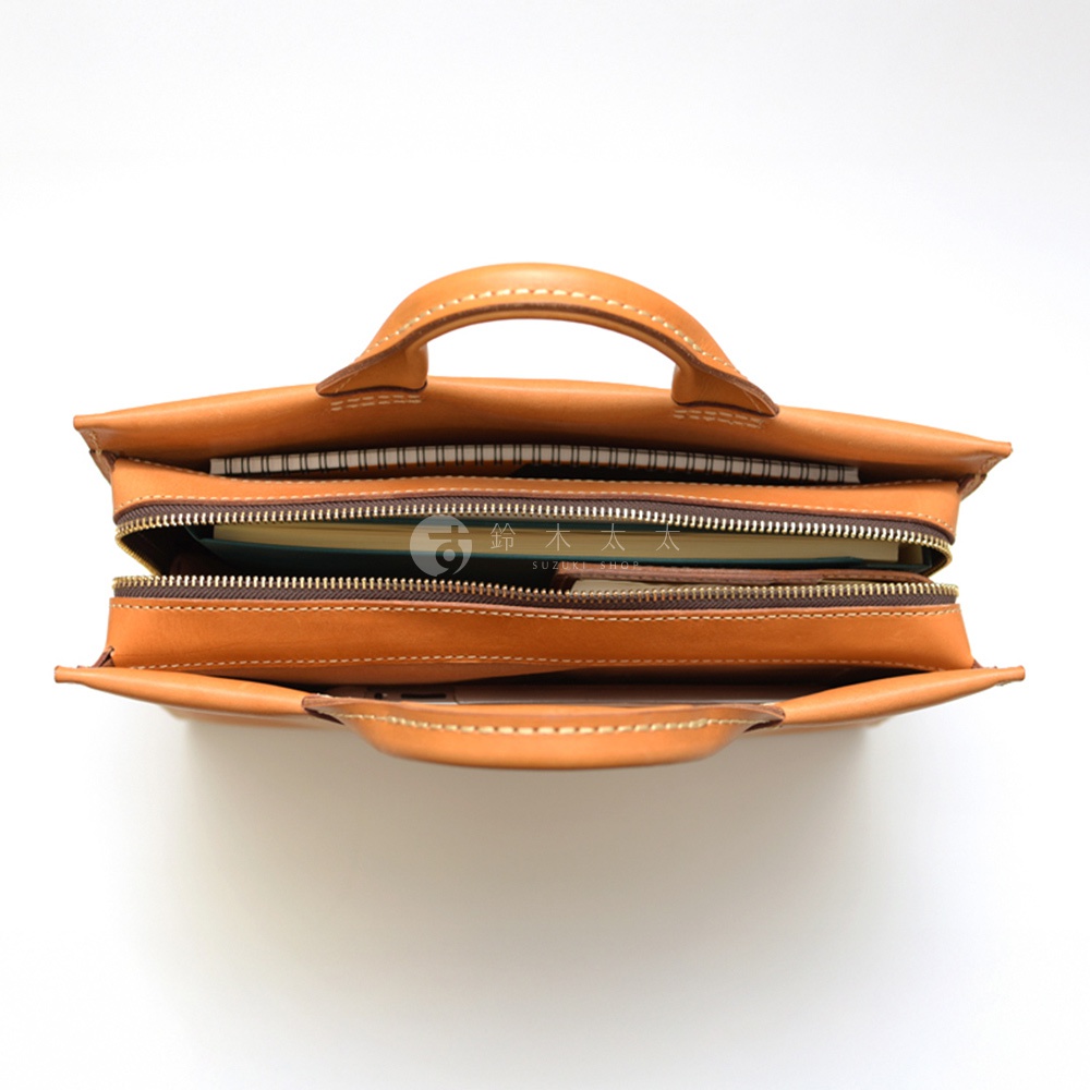 HERZ BW-104 商務公事包，由皮革製成，頂部有提把，中間有拉鍊夾層，裡面放有筆記本。