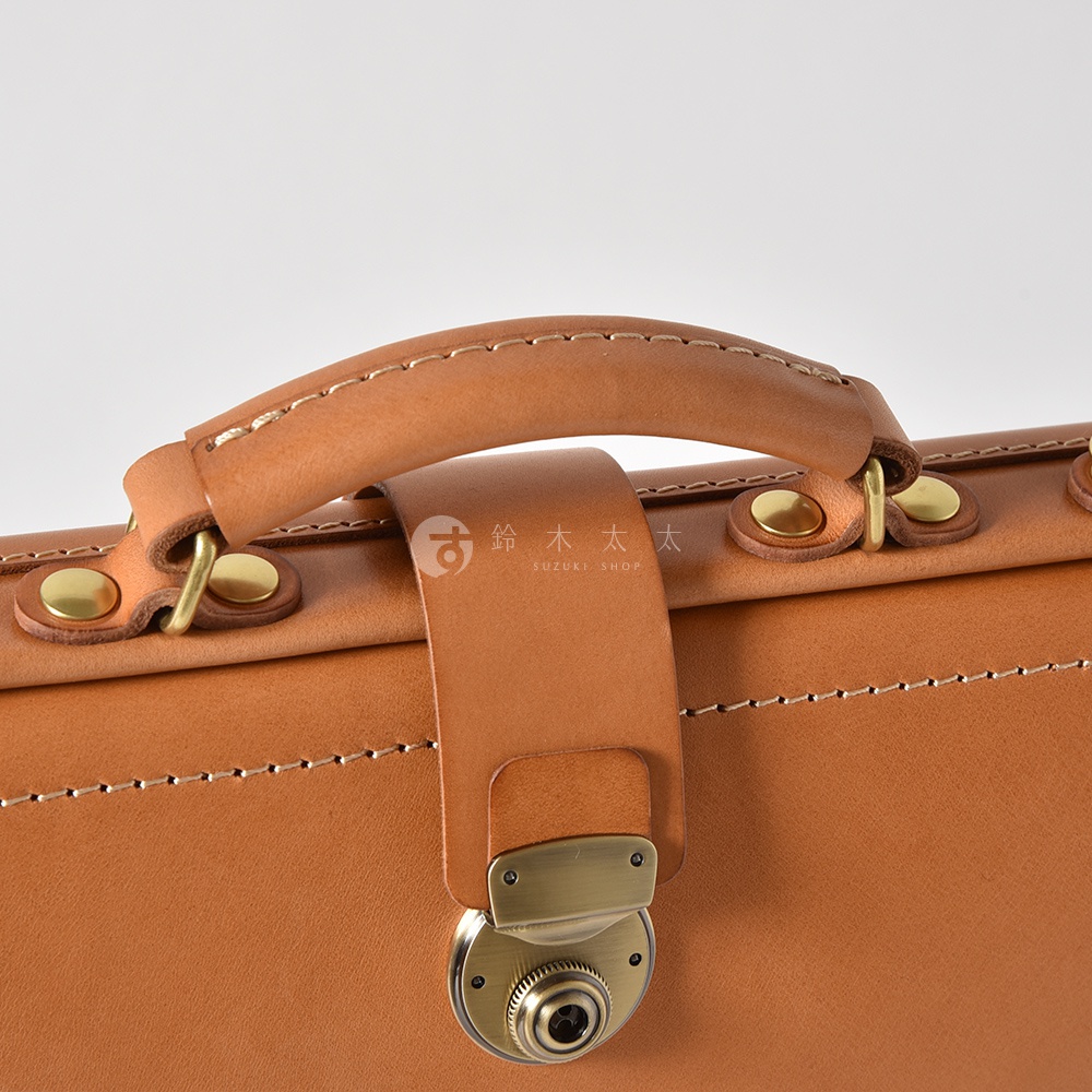 職人手作皮革軟式杜勒斯三用背包 BJ-16，特寫展示棕褐色皮革手把、金屬旋鎖，以及包身縫線和皮革帶扣細節。