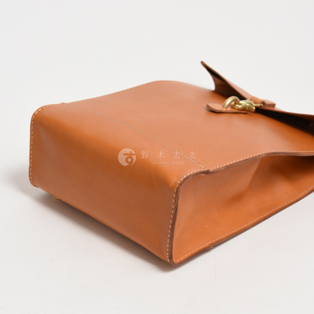 職人手作皮革紙袋風後背包，採用棕色皮革材質，配有金色金屬扣環，設計簡約，縫線精緻。