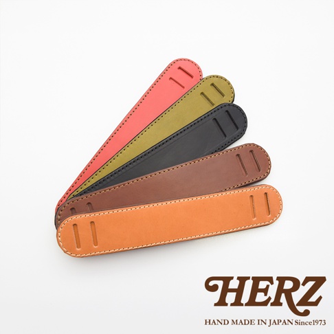 職人手作皮革肩墊，展示紅色、橄欖綠、黑色、棕色和原色皮革，表面有縫線和兩個長方形開口。