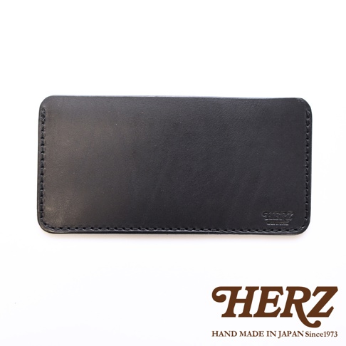 這是一款日本HERZ手工製作的黑色皮革紙鈔收納夾，外觀呈現長方形圓角設計，表面帶有細膩的皮革紋理，右下角壓印有HERZ品牌標誌，整體風格簡約優雅，下方並標示HERZ品牌名稱與職人手作字樣。