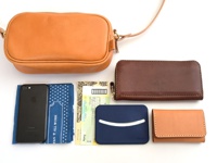 職人手作皮革隨身單肩小包 (CP-35)，搭配棕色皮革長夾、黑色手機、藍色印花布、黃色收據和藍色卡夾。