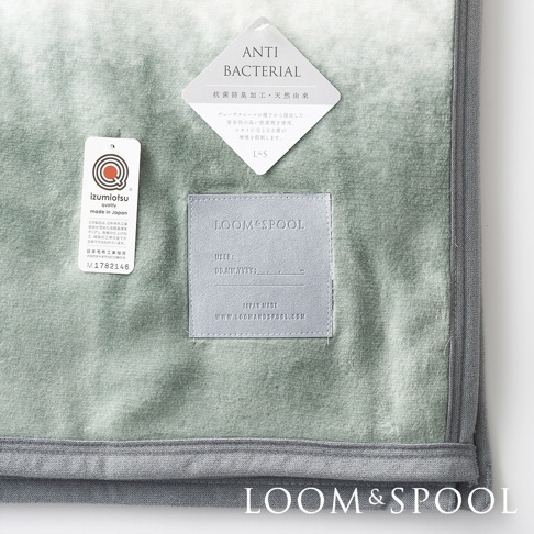 抗菌短絨單人毯，呈現淺綠色漸層，材質柔軟。毯面有「ANTI BACTERIAL」吊牌，標示抗菌防臭加工，以及「LOOM&SPOOL」品牌皮革標籤，註明「JAPAN MADE」。