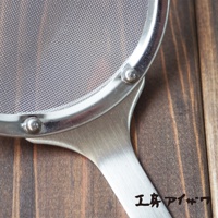 不鏽鋼萬用撈泡勺，帶有細密的銀色濾網和金屬手柄，在木質背景上。