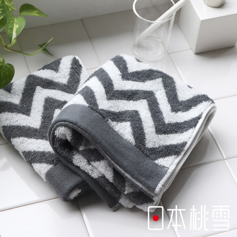 今治北歐方巾，以灰色與白色相間的鋸齒狀幾何圖案織成，材質柔軟，邊緣滾有素色灰色織帶。