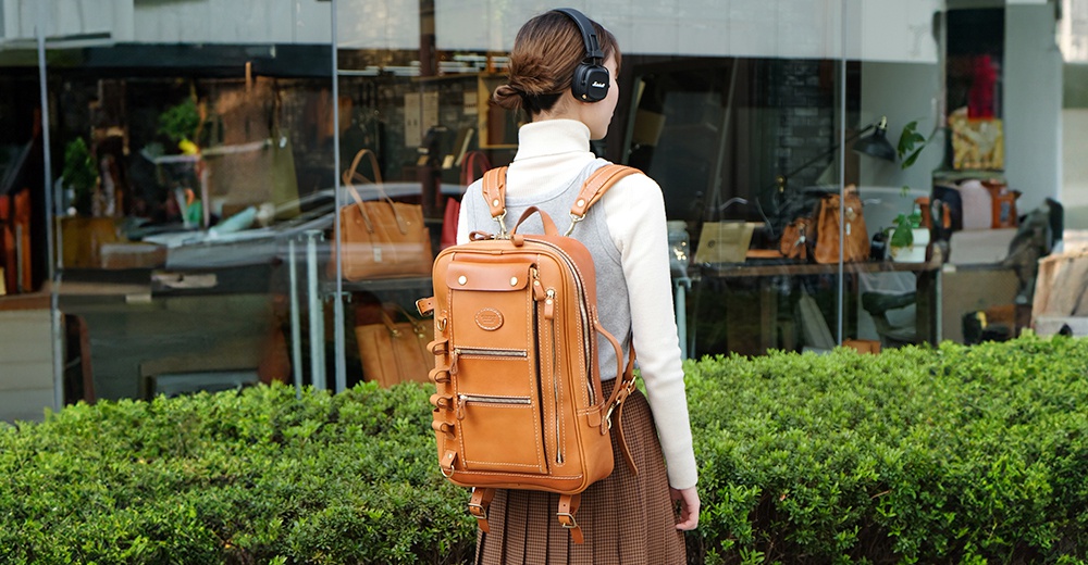 職人手作皮革兩用後背包，經典棕色，方形包體設計，前有雙拉鍊口袋與翻蓋口袋，側邊有可調式束帶，背帶可拆卸。