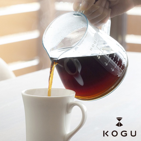 手持透明Tritan材質的700ml咖啡壺，將深褐色咖啡液倒入白色馬克杯中，咖啡壺上有明顯的刻度標示。