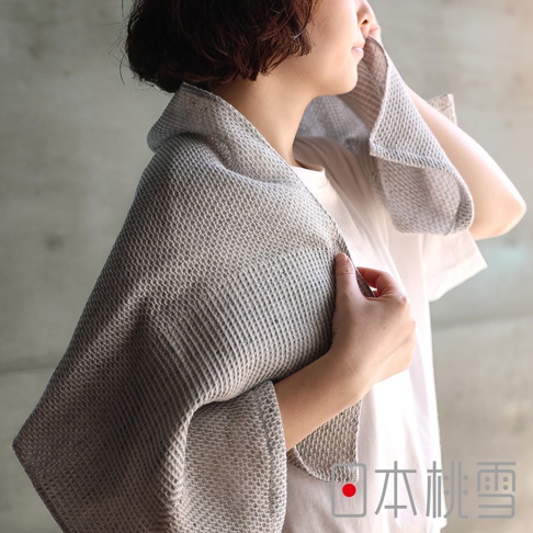 日本桃雪品牌字樣，女子手持竹炭色檜木鬆餅紋迷你浴巾擦拭臉部