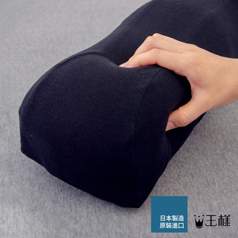 深藍色織物材質的抬腿枕，一隻手壓在枕頭上，顯示其柔軟度。