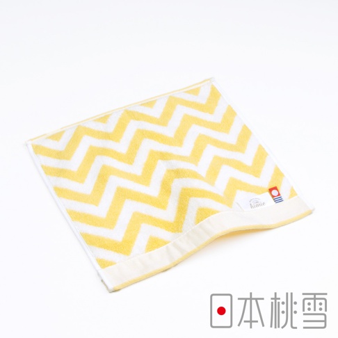 今治北歐方巾，採用黃色與白色相間的鋸齒狀圖案，材質為柔軟的棉，邊緣有品牌標籤。