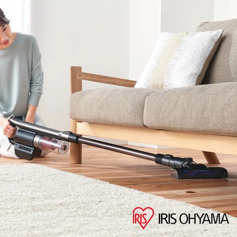 灰色與黑色的氣旋式超輕量無線手持吸塵器，配有透明集塵筒，正在清潔木質地板與白色地毯。