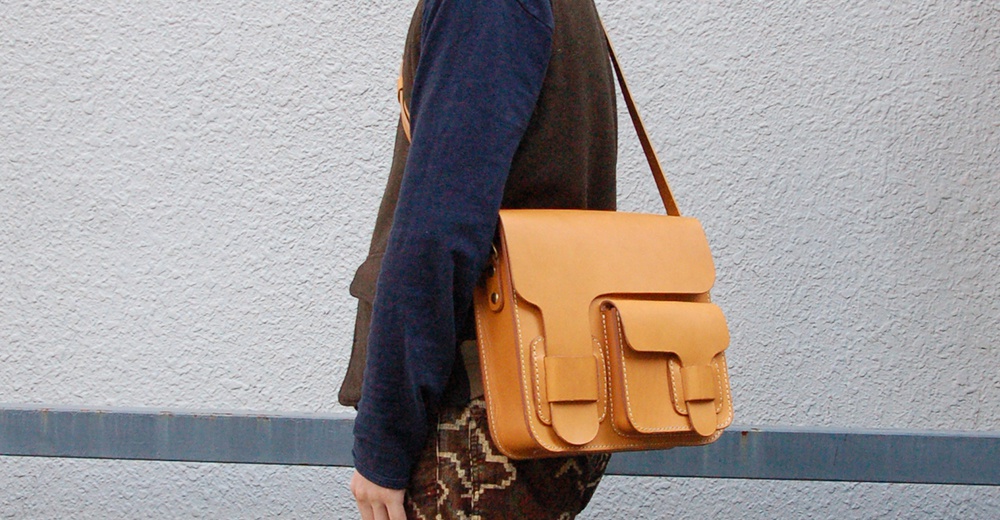 職人手作皮革經典厚實單肩包，淺棕色皮革，方正包型，正面有兩層翻蓋式前袋，搭配縫線細節，可斜挎。