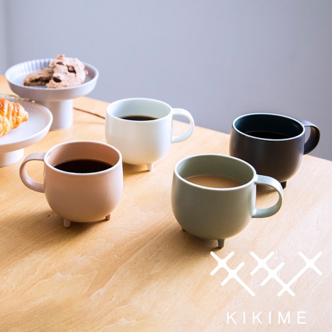 四個美濃燒珪晶釉球型馬克杯，分別為淡粉色、白色、淺綠色和黑色，均有三個支腳設計，杯內盛有咖啡或茶飲，擺放在木質桌面上。