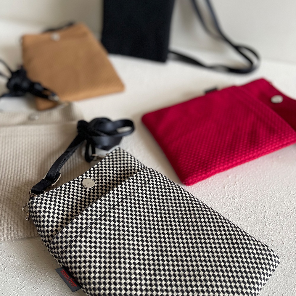 多款三河木綿刺子織手機包，包含黑白格紋、卡其色、紅色及黑色，設計簡約，附有細長背帶。