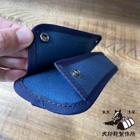 深藍色純棉帆布製成的肩墊，帶有金屬按鈕，邊緣有深藍色織帶包邊。