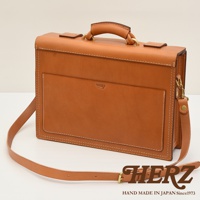 棕色皮革製成的兩用機師箱，有手提把和可拆卸斜肩帶，箱面有品牌壓印和縫線裝飾，整體風格簡潔。